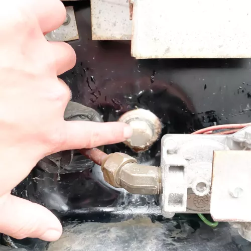 A hand pointing to a water heater valve